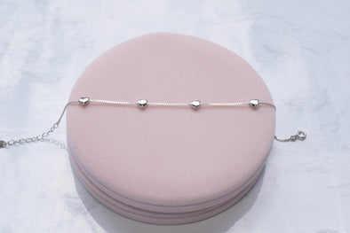 Pulsera con corazones en plata 925 sobre superficie rosa
